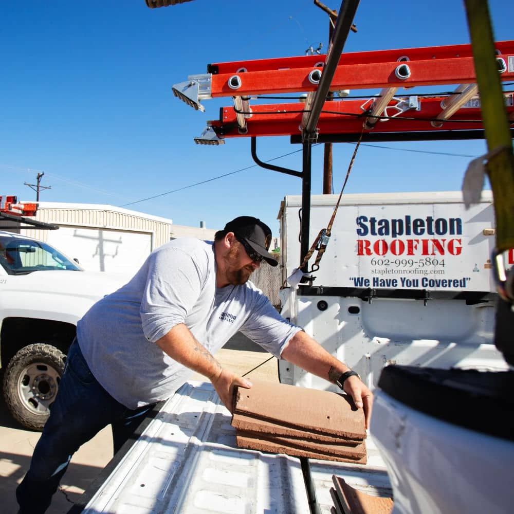 stapleton phoenix az roofing company employee picking up roofing tiles for roof installation in phoenix