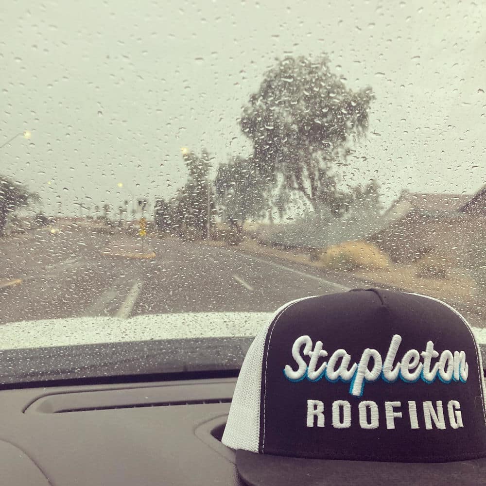 stapleton roofing hat on a dashboard. Rain from the monsoon season is outside.